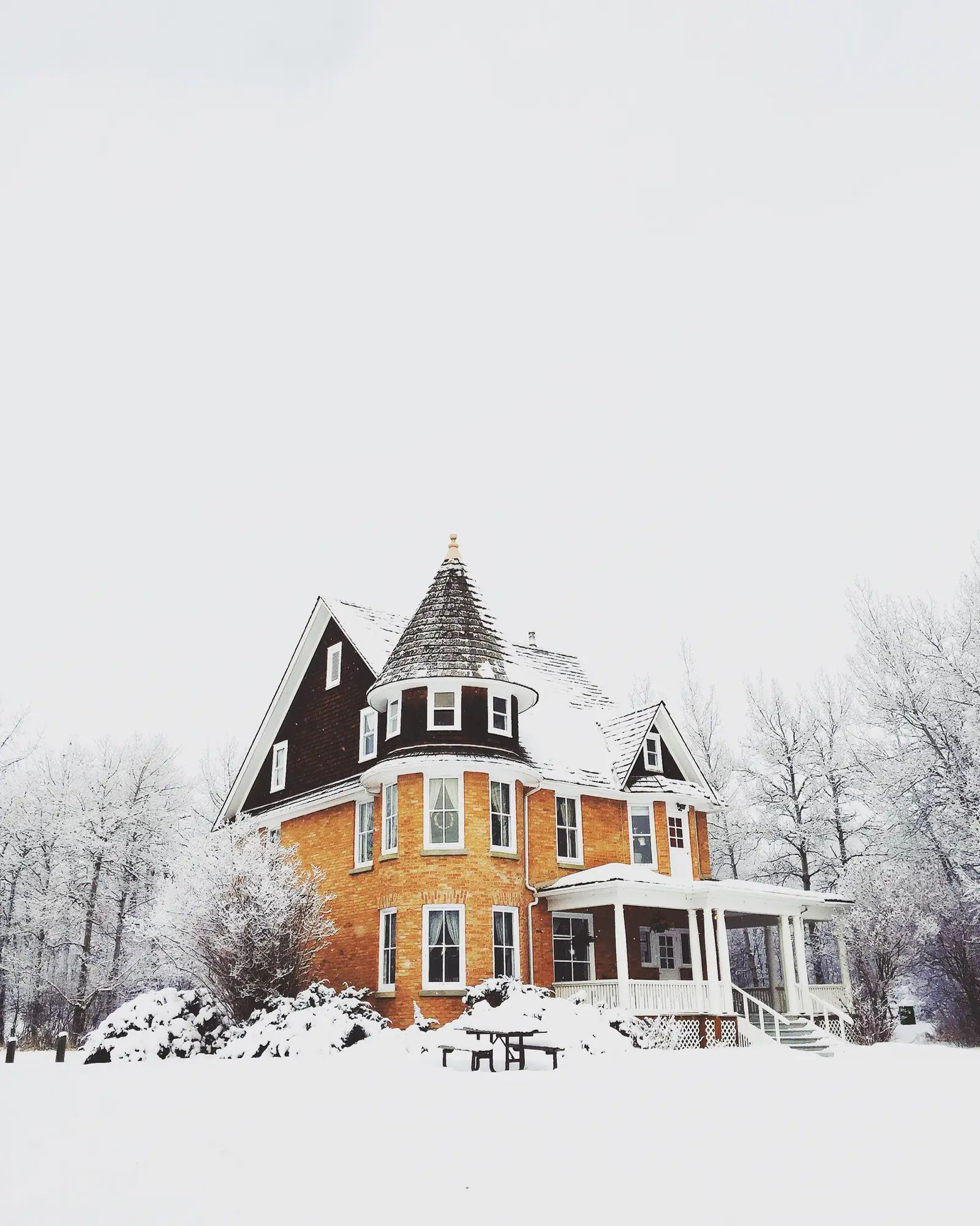 A two-story house with a wide porch under fresh snow, the home that secures a cash-out refinance